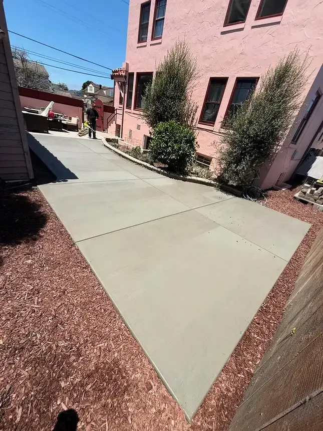 New concrete walkway beside a residential building with landscaped mulch borders