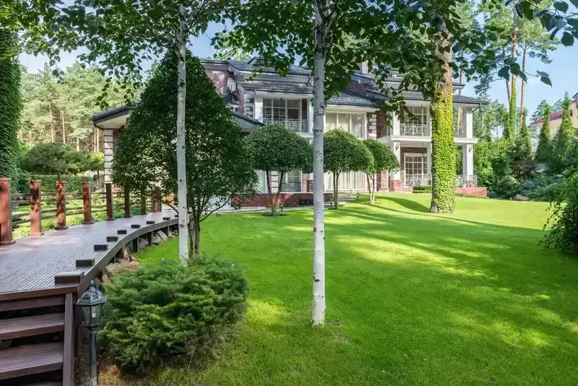 Landscaped lawn with curved wood walkway beside a large home