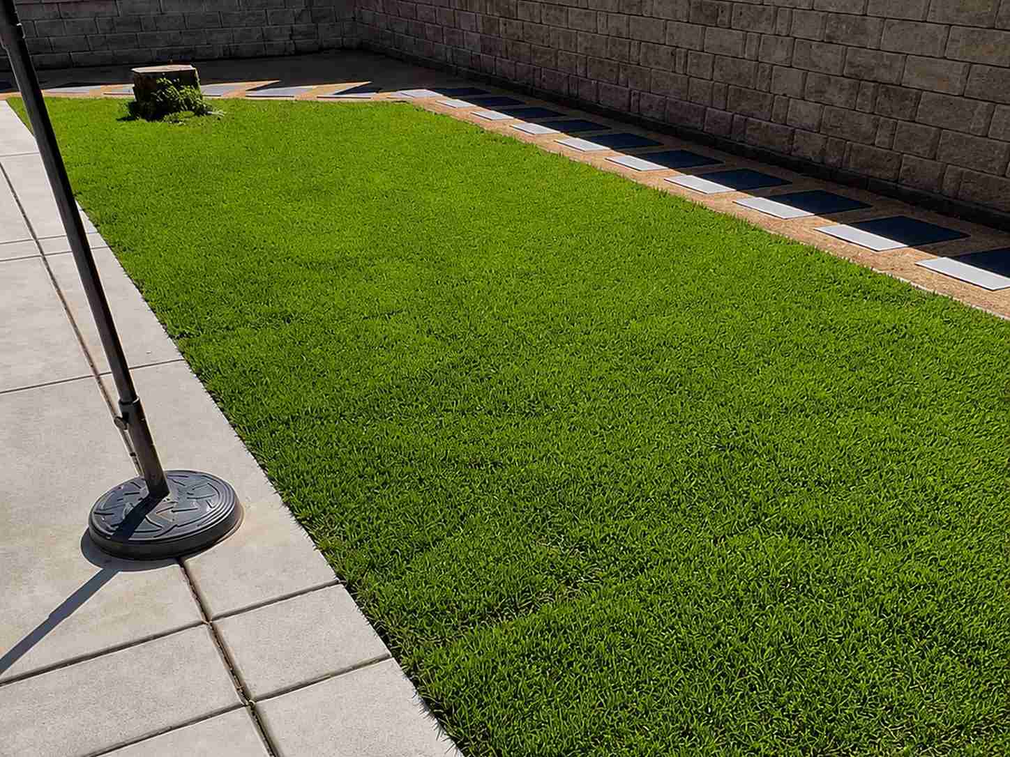 Finished artificial turf lawn with concrete patio and stepping-stone border