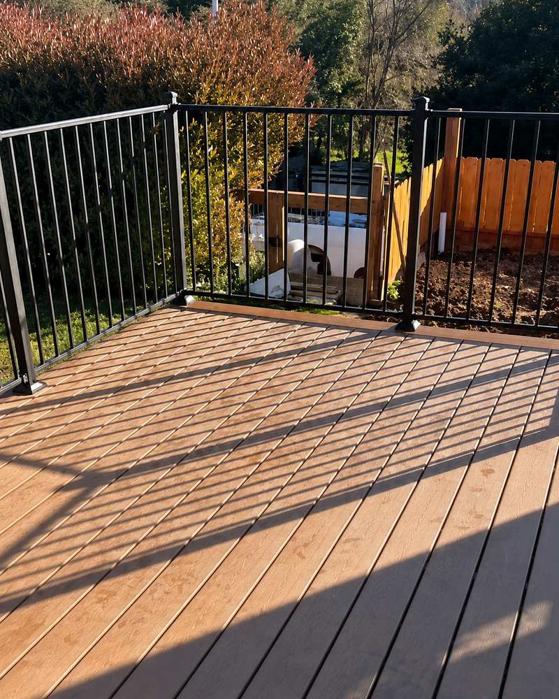 Finished wood deck and black metal railing overlooking the backyard