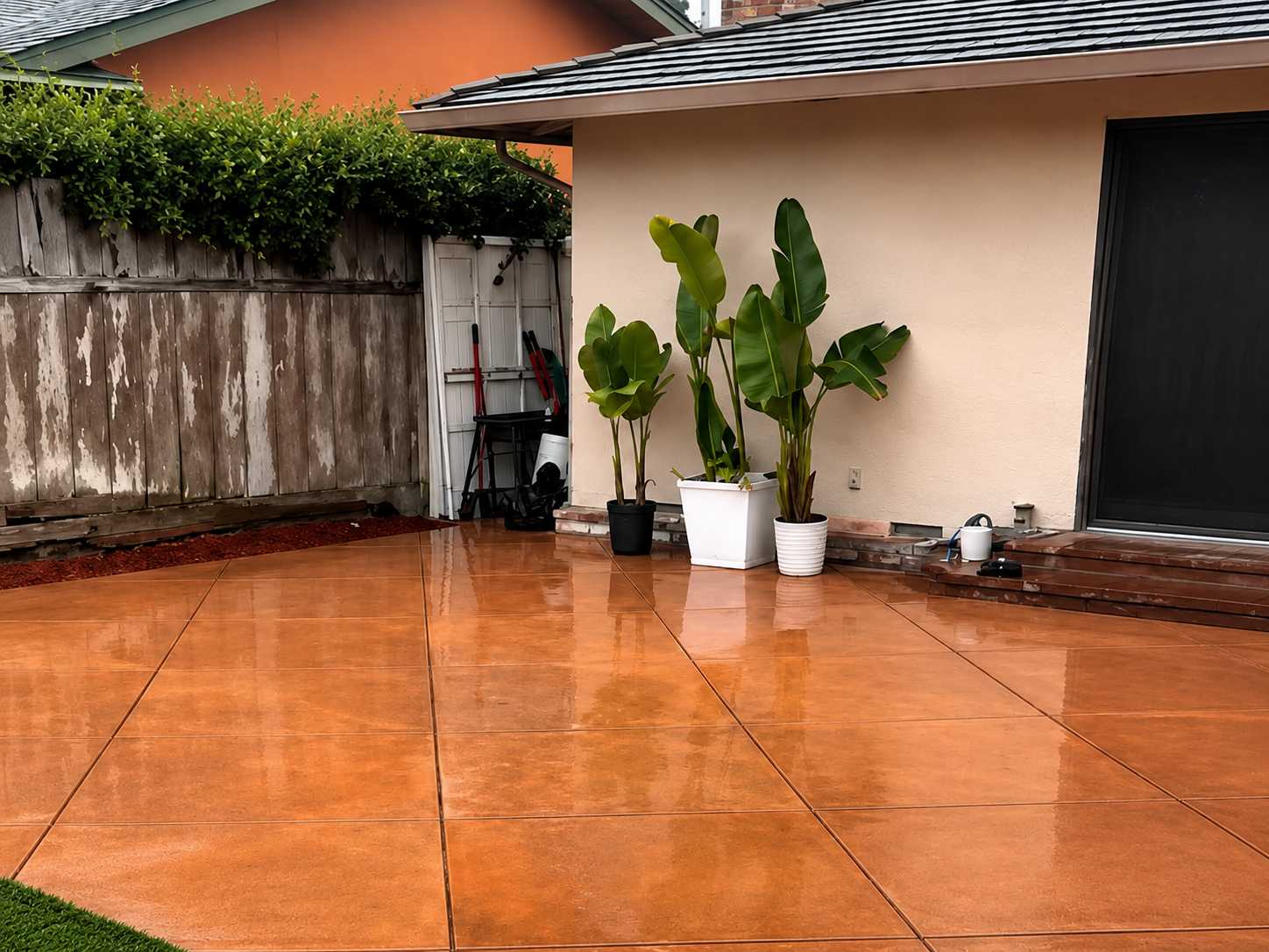 Orange stamped concrete patio with a wet-look finish beside a residential home