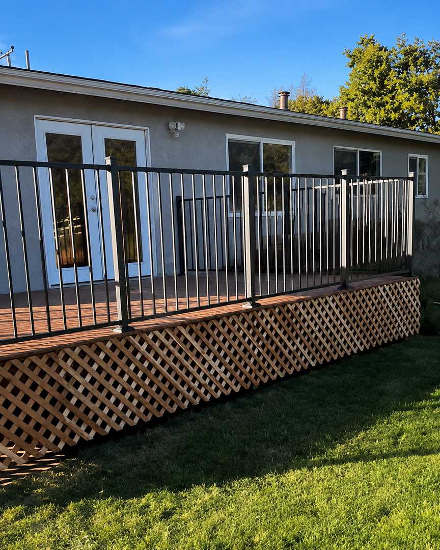Raised backyard deck with black railing and wood lattice skirting